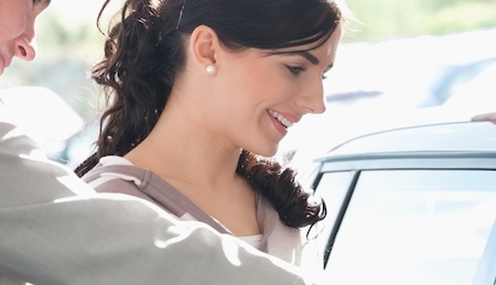 Car dealer pointing the interior of a car with a woman in a car shop