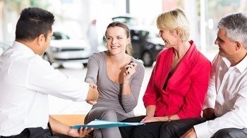car salesman handshaking with young buyer