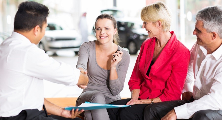 car salesman handshaking with cheerful young buyer